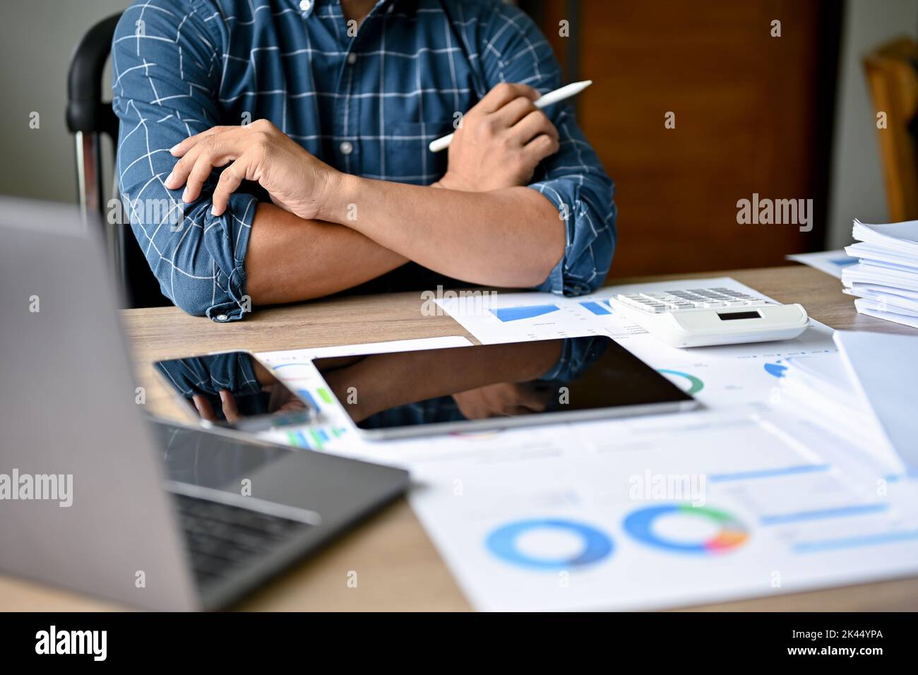 Ein intelligenter und professioneller asiatischer Geschäftsmann oder männlicher Chef kreuzte die Arme, sitzt an seinem Schreibtisch und arbeitet und plant an seinem finanziellen Investitionsproj Stockfoto