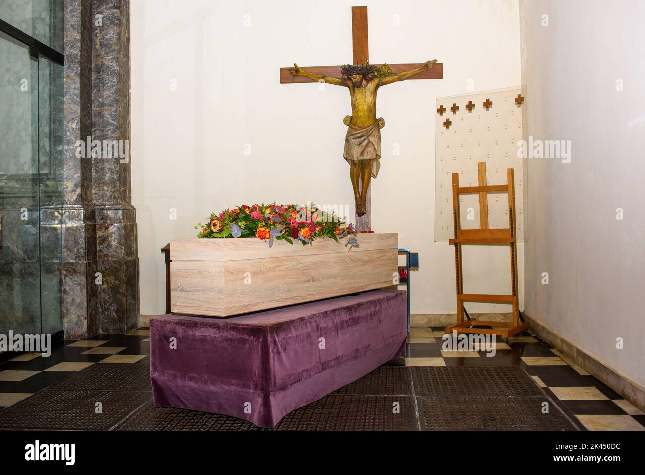 Sarg mit Blumen auf ihm in der Kirche mit Jezus Christus an der Wand warten auf den Transport für den Gottesdienst Stockfoto