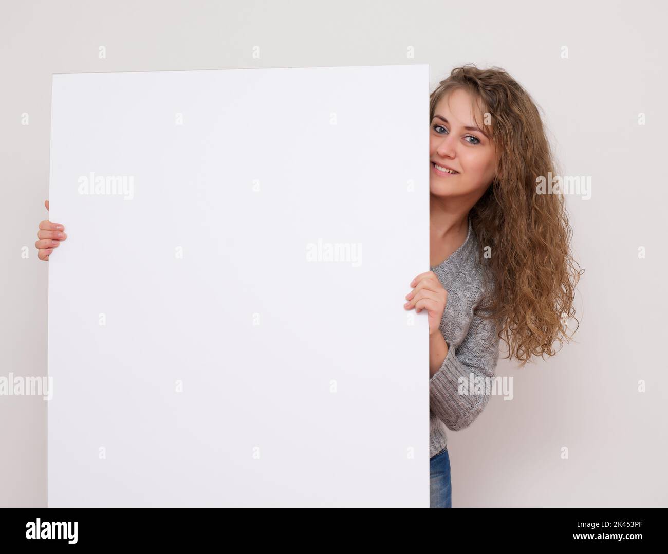 Hübsche Frau posiert hinter einem weißen Panel isoliert auf weißem Hintergrund Stock Foto Stockfoto
