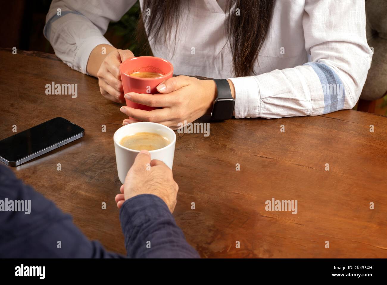 Paar sitzt im Café, beschnittenes Bild des Paares sitzt im Café. Trinken heißen frischen Kaffee. Sich gegenseitig sprechen. Dating-Konzept mit Kopierraum. Stockfoto