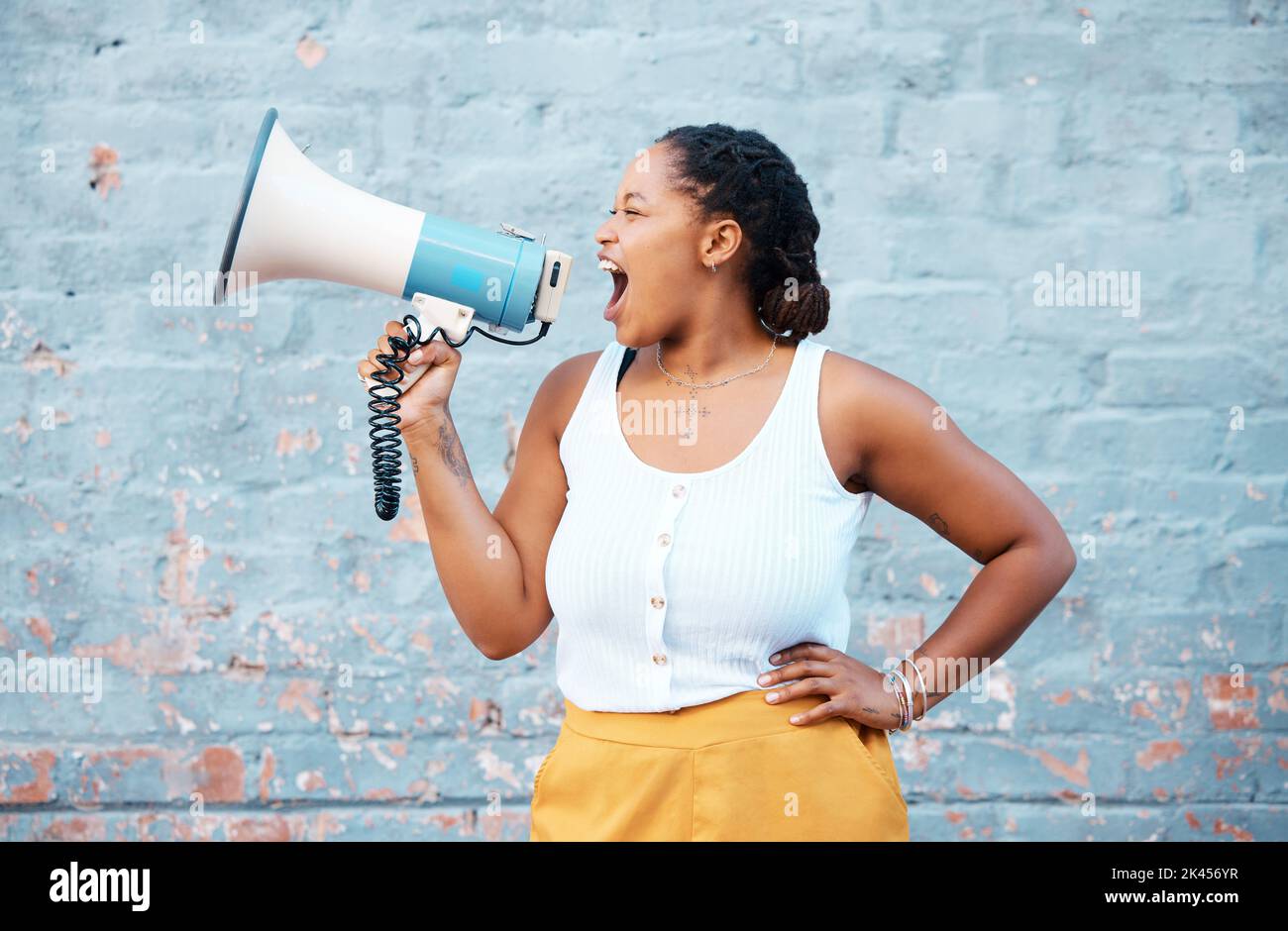 Schwarze Frau, Megaphon-Lautsprecher und Ansage auf Wandhintergrund für Rede, Protest und wütende Stimme. Feministische Kundgebung kämpft für Menschenrechte, Gerechtigkeit Stockfoto