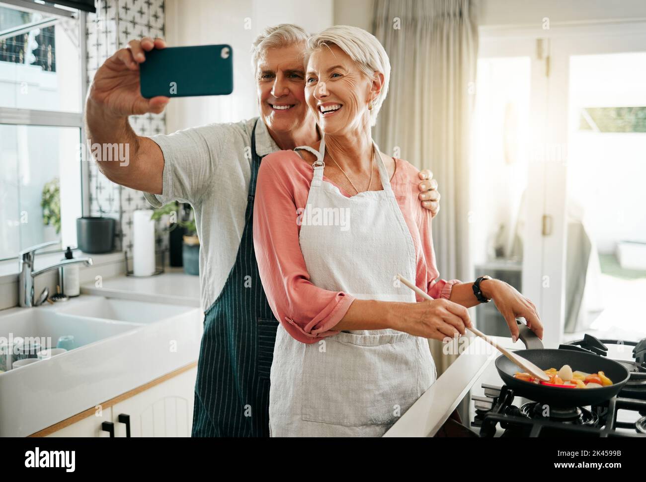 Altes Paar, Telefon Selfie und Kochen in der Küche, leckeres Essen und Essen zu Hause. Liebe, Lächeln und glücklich ältere Rentner romantischen Mann und Frau kochen Stockfoto