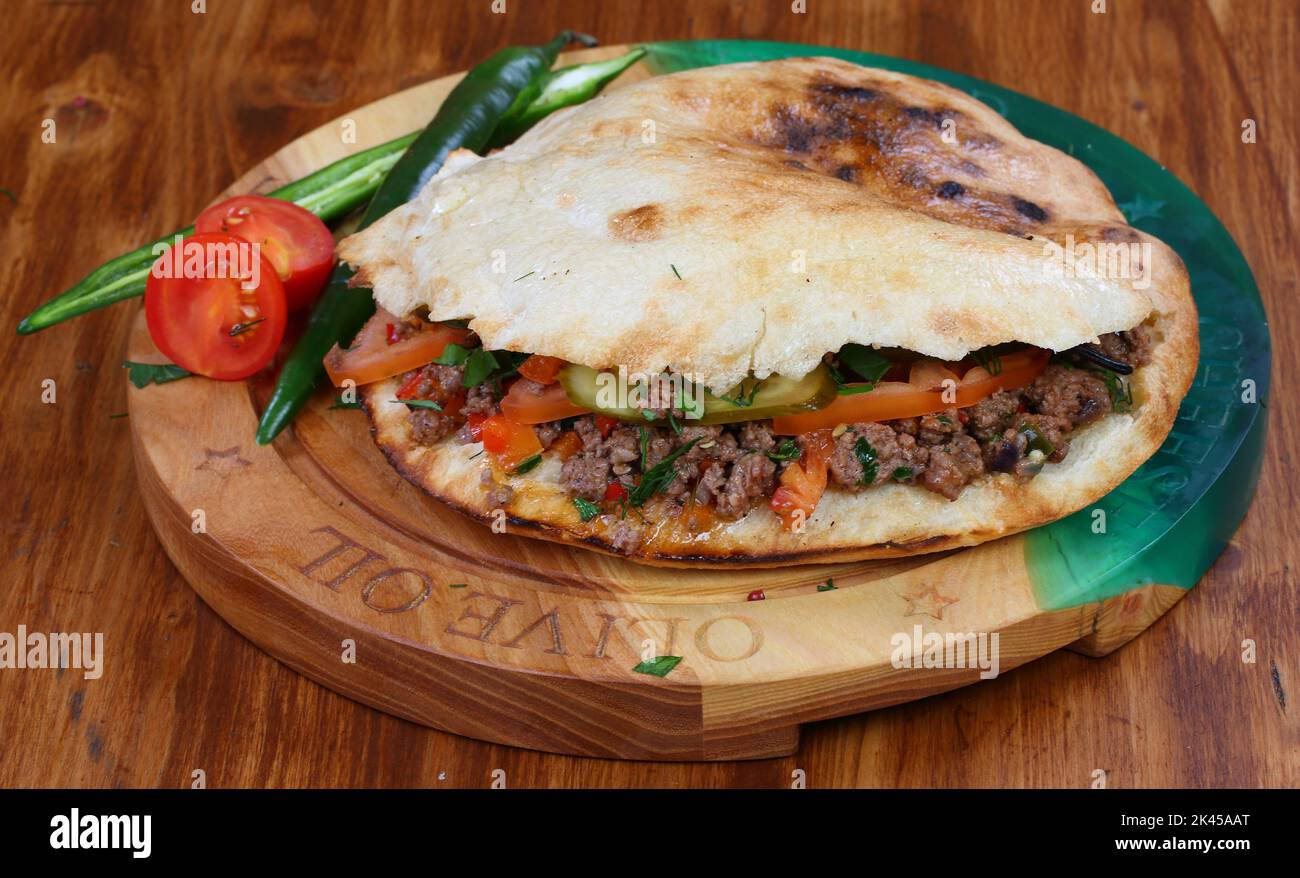 Rolle gefüllt mit Shish Kebab mit Tomaten, Kräutern, Ketchup und Amyonnaise auf einem Holztisch Stockfoto