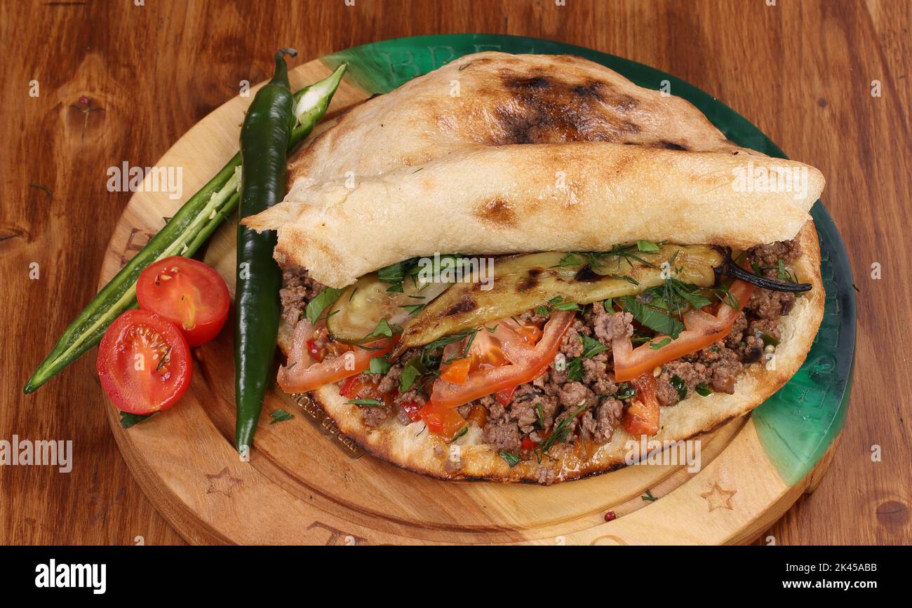 Rolle gefüllt mit Shish Kebab mit Tomaten, Kräutern, Ketchup und Amyonnaise auf einem Holztisch Stockfoto