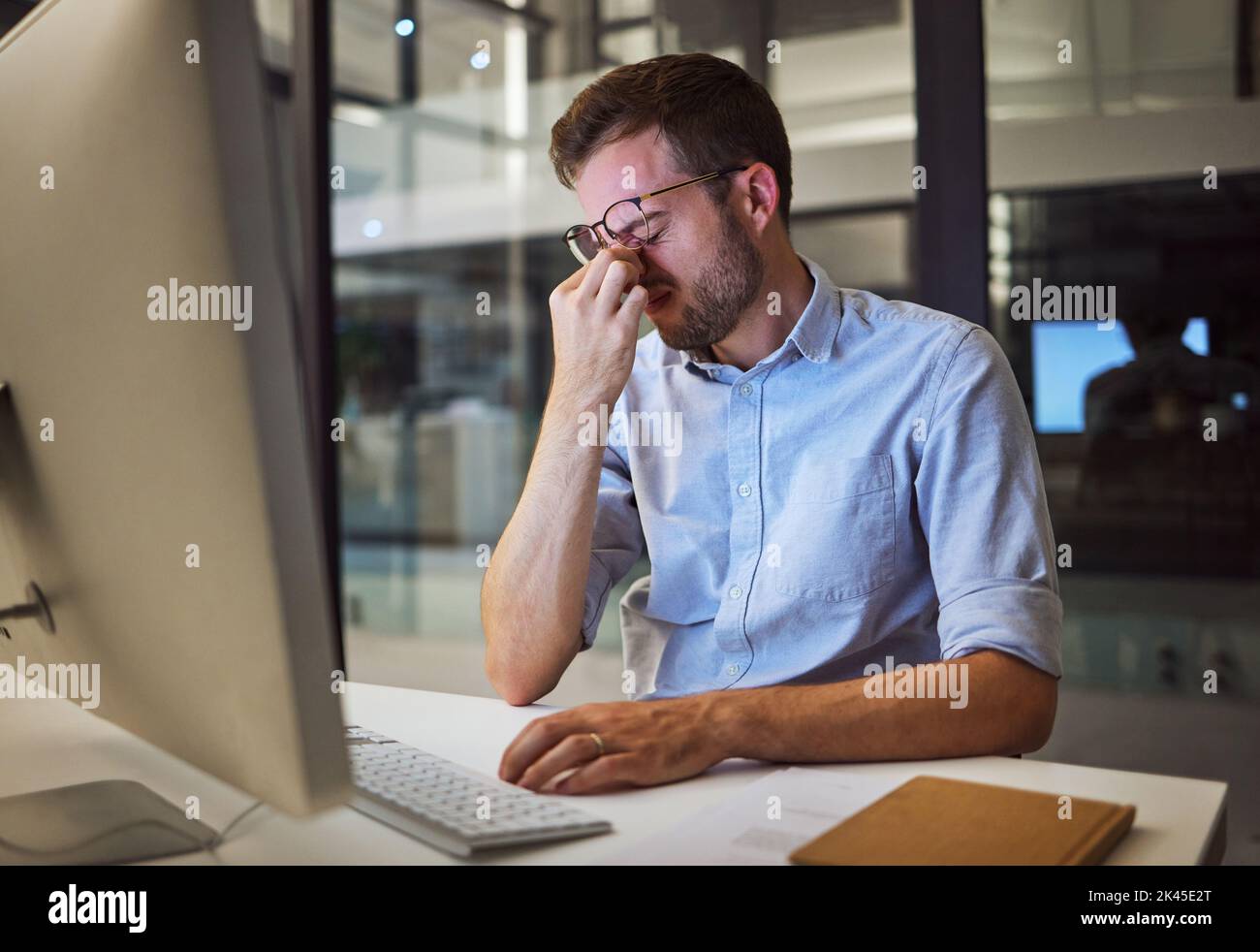 Nachtarbeit, Stress und müde Mann, der an seinem Computertisch sitzt, mit Kopfschmerzen, Depressionen und Burnout vom Arbeitsdruck. Gestresst, psychische Gesundheit Stockfoto