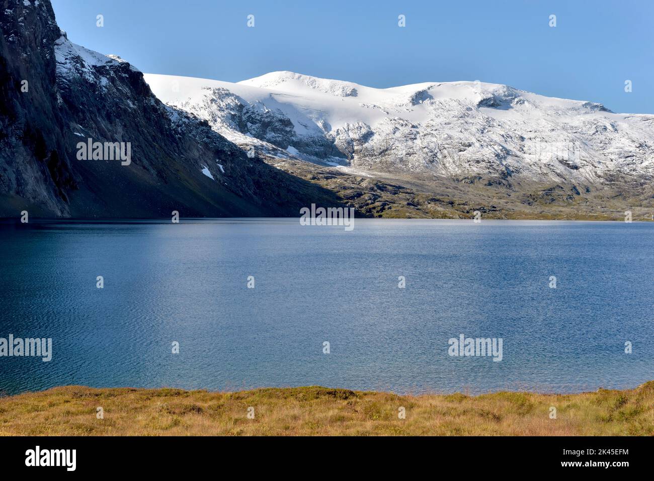 Schöner blauer See in den schneebedeckten norwegischen Bergen unter blauem Himmel Stockfoto