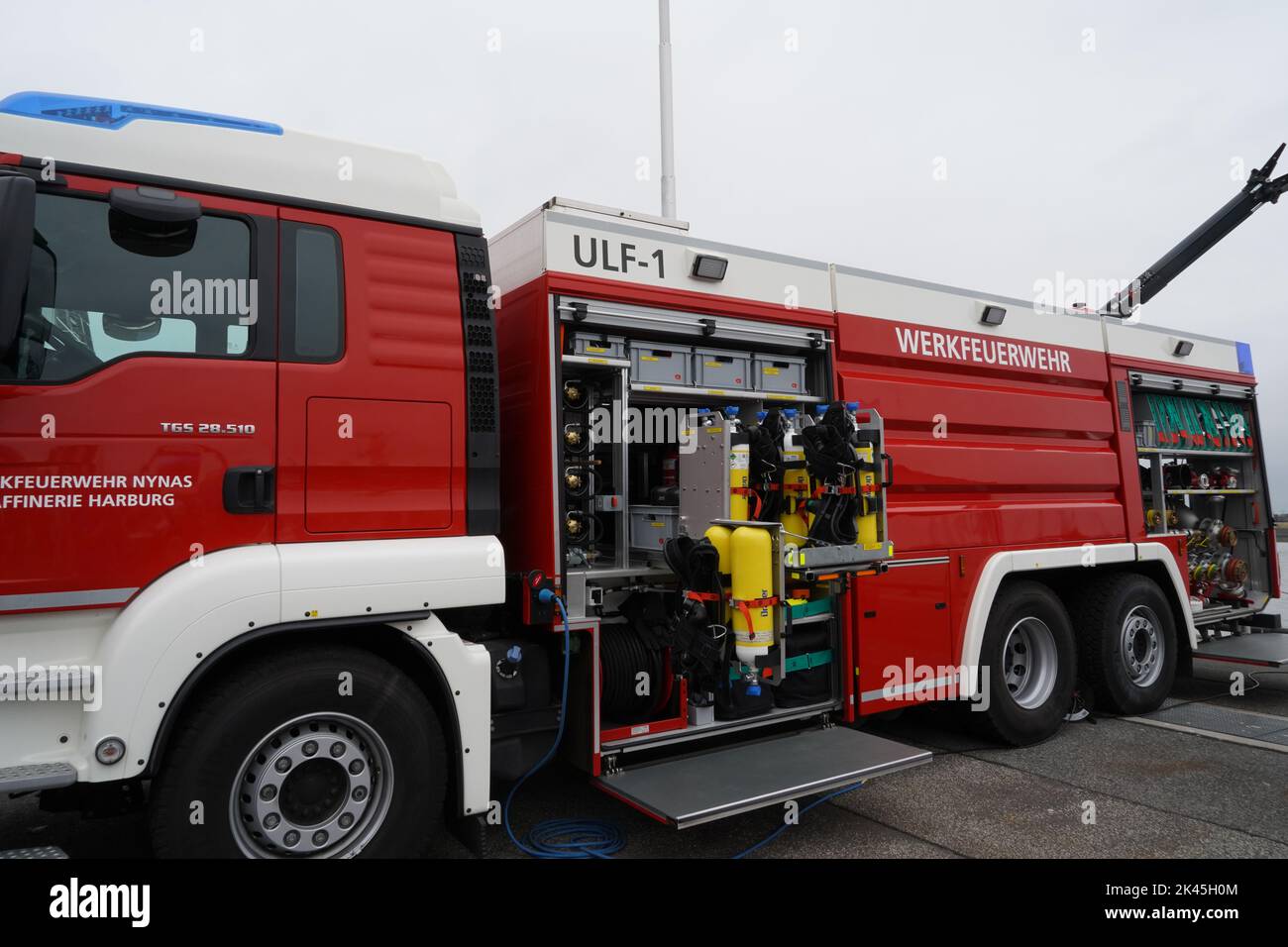 Blick auf den roten Feuerwehrwagen mit offener Seitentür, wo sich die Löschausrüstung befindet. Stockfoto