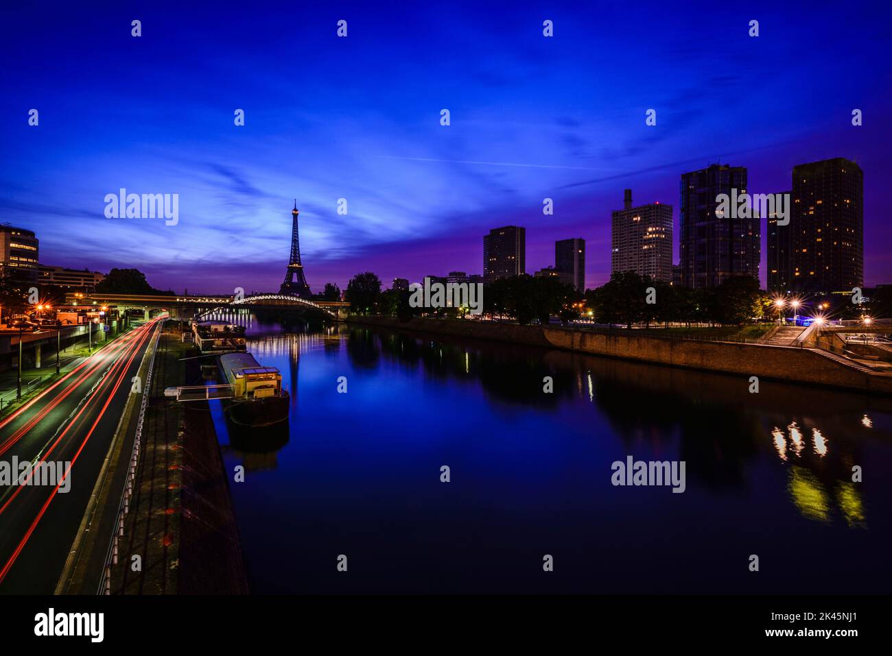 Ein Blick auf das Wasser der seine bei Nacht, hohe Gebäude am Flussufer, der Eiffelturm in der Ferne. Stockfoto