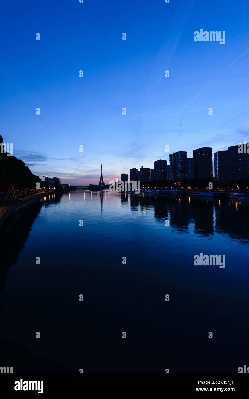 Ein Blick auf das Wasser der seine bei Nacht, hohe Gebäude am Flussufer, der Eiffelturm in der Ferne. Stockfoto