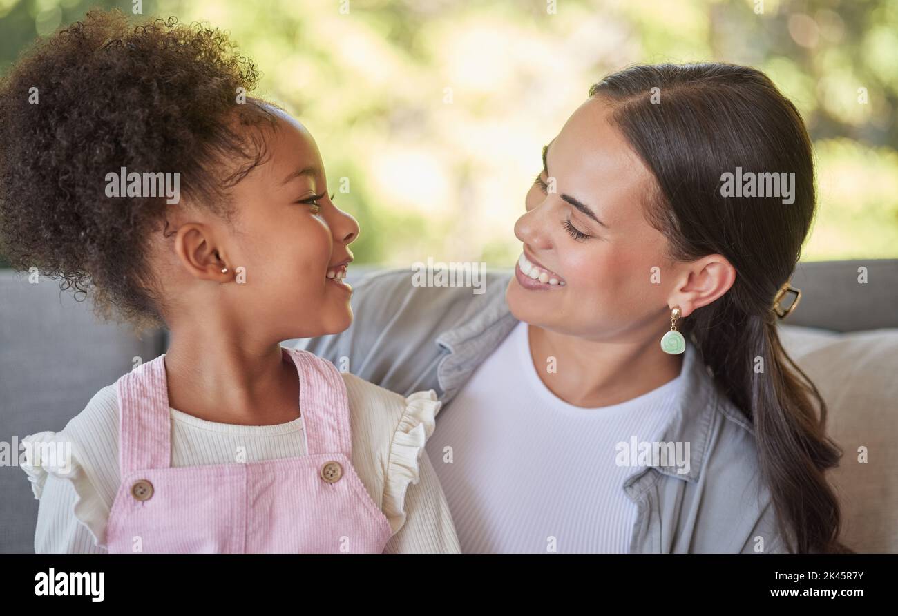 Liebe, Mutter und lächle mit ihrem Mädchen, während sie sich entspannen und auf der Couch zu Hause lachen. Süßer Moment zwischen lateinischer Frau und Kind beim Binden, Glück Stockfoto