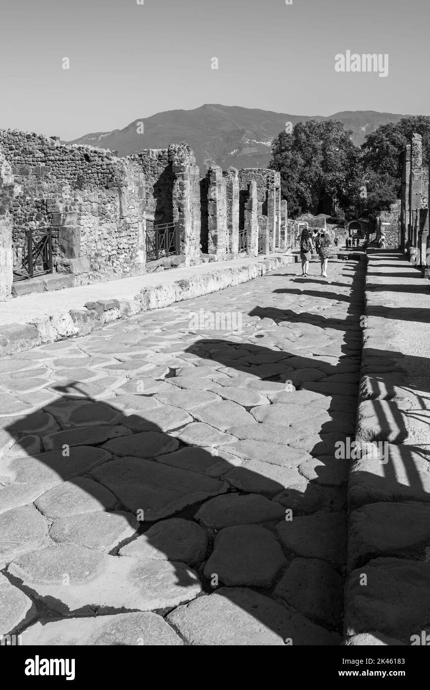 Schwarz-Weiß-Foto, auf dem Touristen entlang der antiken Pompeji-Straße spazieren Stockfoto