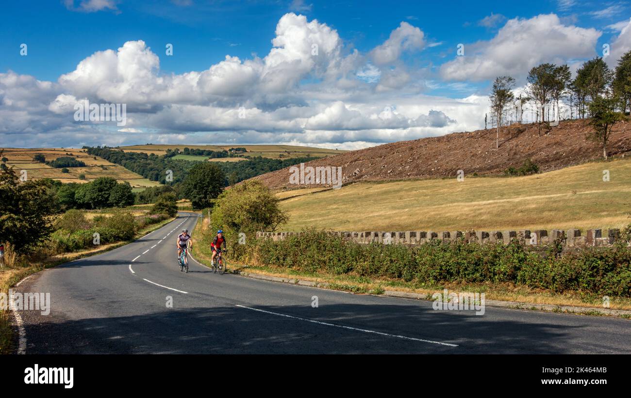 Zwei männliche Zylisten, die eine der 100 Classic-Anstiege Großbritanniens, Norwood Edge, mit Blick auf das Washburn Valley, besteigt haben. North Yorkshire, Großbritannien Stockfoto