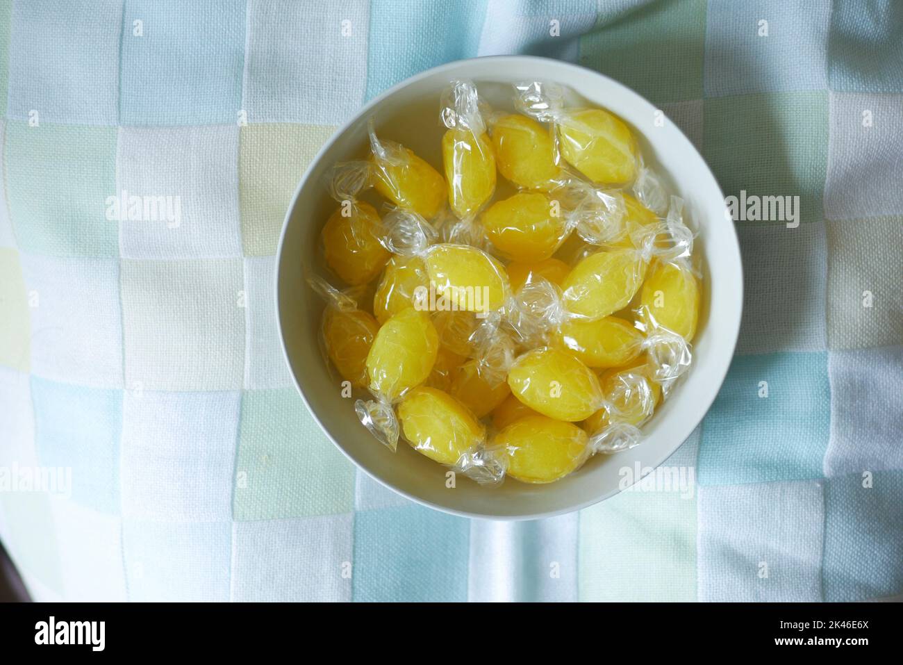 Gelbe Süßigkeiten in weißer Schale auf Tischdecke Stockfoto