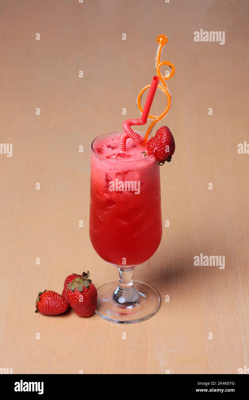 Ein Glas Erdbeersaft mit frischem Obst ist klassisch auf einem Holztisch zum Dessert dekoriert Stockfoto