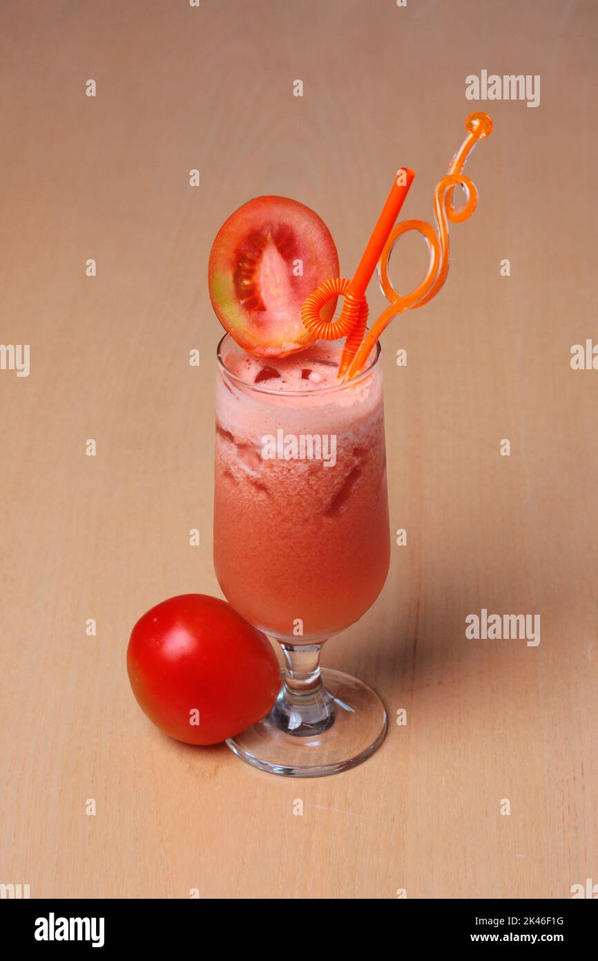 Ein Glas Tomatensaft mit frischem Obst ist klassisch auf einem Holztisch zum Nachtisch dekoriert Stockfoto