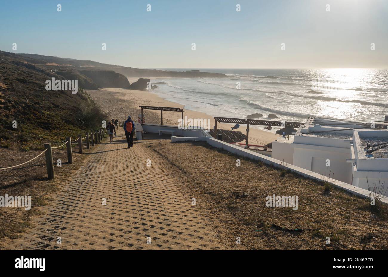 Almograve, Odemira, Portugal, 26. Oktober 2021: Pfad zum Sandstrand Praia Grande de Almograve mit Gruppe von Menschen und Restaurant. Goldene Stunde Stockfoto