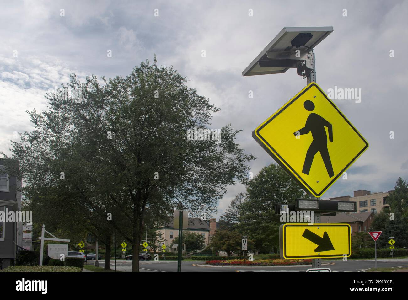 Hellgelb und schwarz Walk-Stret-Crossing-Schild mit Licht und Sonnenkollektoren Stockfoto
