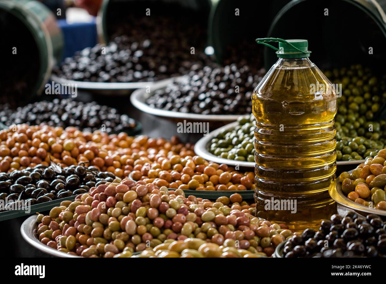 Hintergrund von Oliven und einer Flasche Olivenöl auf einem Obst- und Gemüsemarkt. Selektiver Fokus Stockfoto
