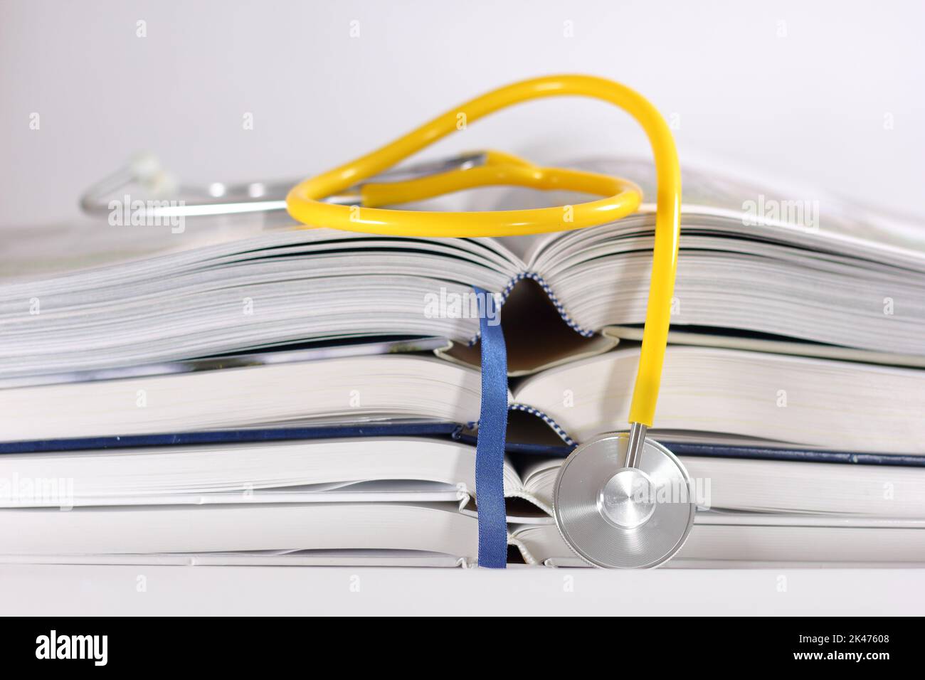 Stethoskop und Stapel geöffneter Bücher isoliert auf weißem Hintergrund. Medizinisches Berufsbildungskonzept und Informationskonzept. Stockfoto
