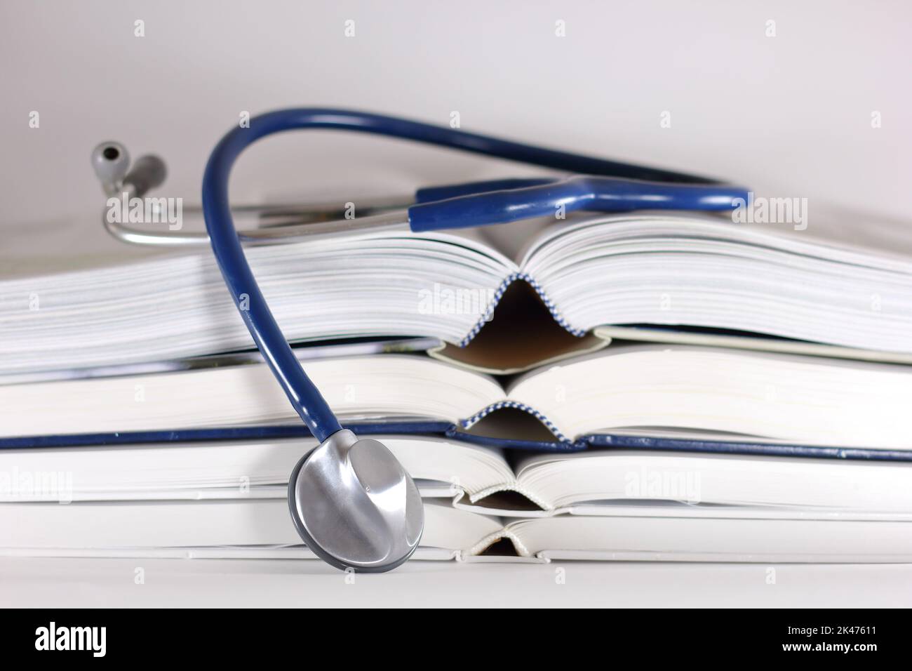 Stethoskop und Stapel geöffneter Bücher isoliert auf weißem Hintergrund. Medizinisches Berufsbildungskonzept und Informationskonzept. Stockfoto