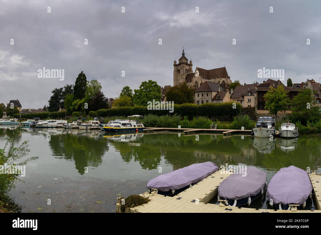 Dole, Frankreich - 14. September 2022: Blick auf den Doubs-Fluss in Dole mit der Kirche auf dem Hügel und Hausbooten, die am Flussufer festgemacht sind Stockfoto