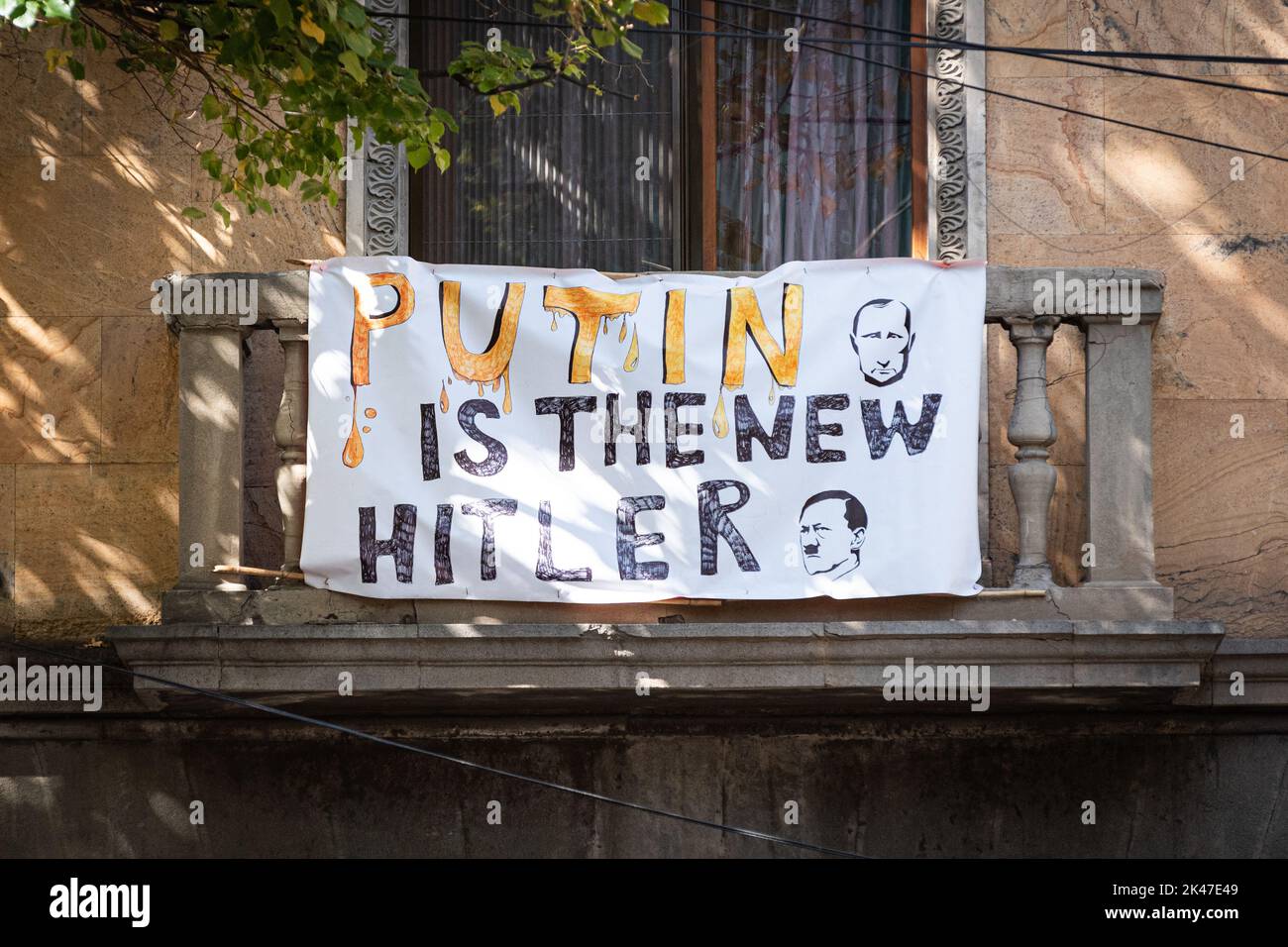 Tiflis, Georgien - 18. September 2022: Ein Plakat auf dem Balkon eines Wohnhauses, das sagt, Putin sei der neue Hitler. Stockfoto