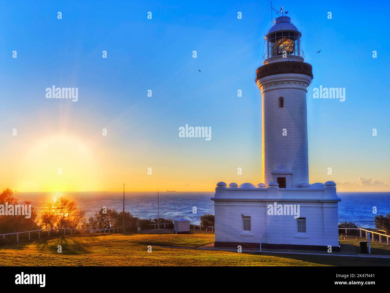 Aufgehende Sonne über dem pazifischen Ozeanhorizont vor dem Leuchtturm Norah Head an der australischen Zentralküste. Stockfoto