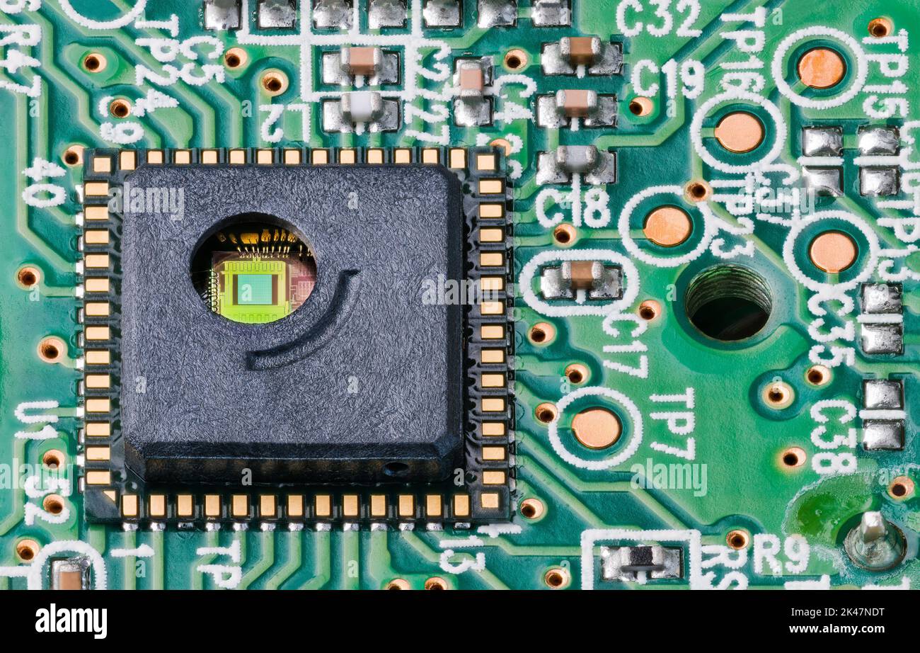 Grüner Silizium-Chip und goldene Drähte in der runden Bohrung des integrierten Schaltkreises. Nahaufnahme des optoelektronischen Sensors auf der Leiterplatte von der Maus des optischen Lasercomputers. Stockfoto