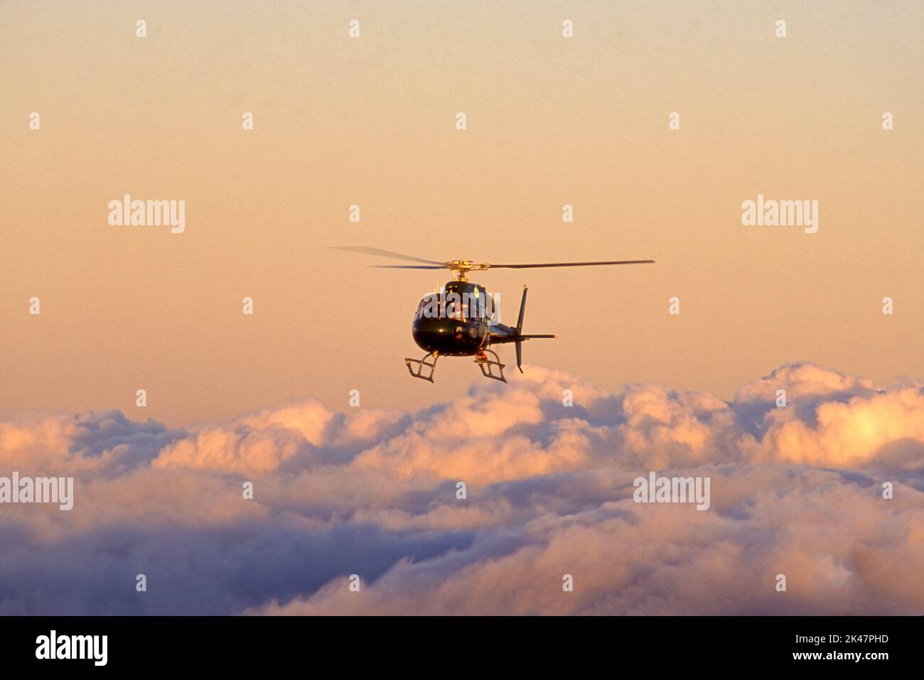 Helikopter fliegt bei Sonnenuntergang über Wolken. Stockfoto
