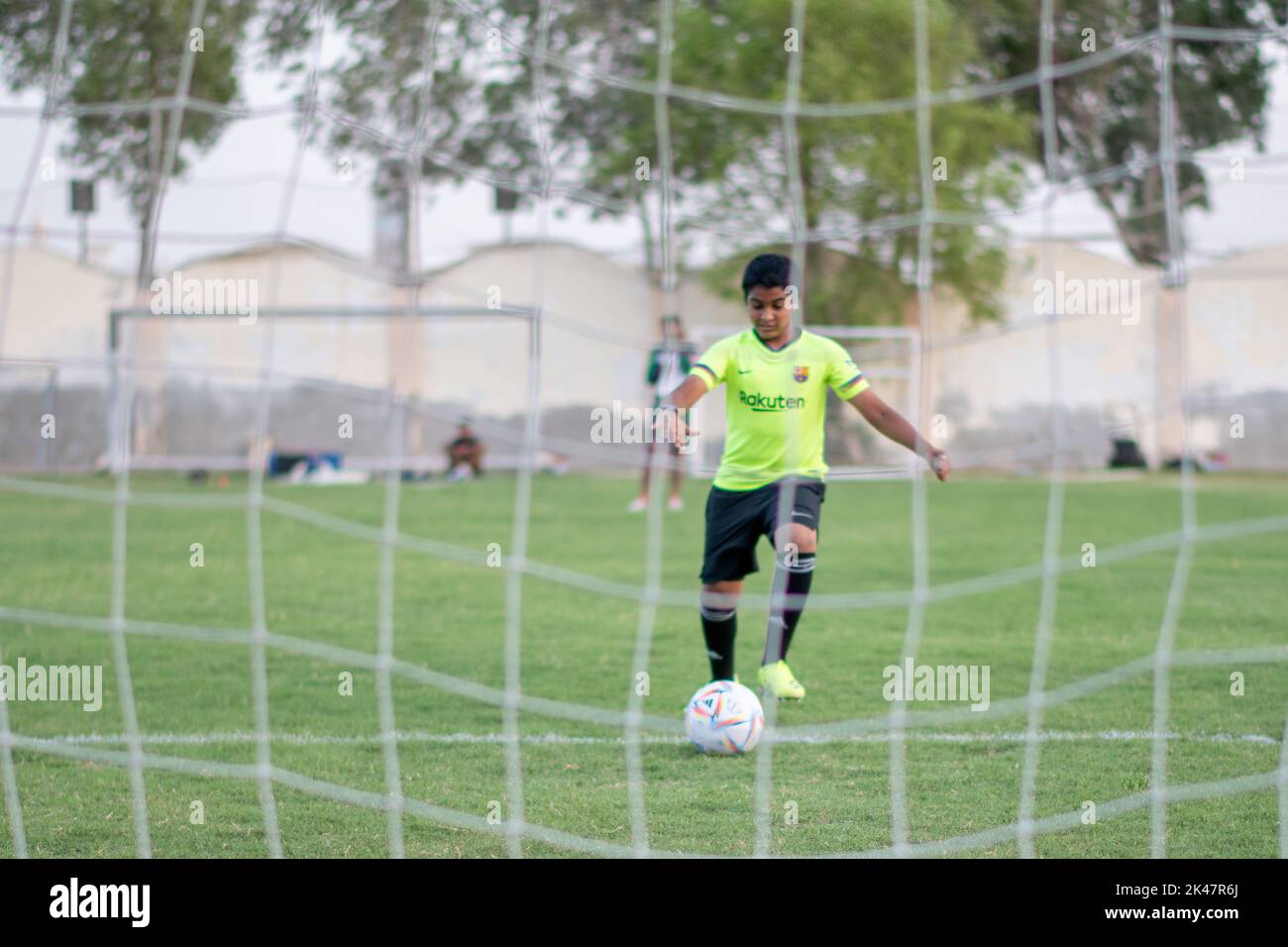 Fußballspieler für junge Kinder, der mit dem offiziellen FIFA Qatar Match Ball auf der Straße spielt. Al-Rhila Stockfoto