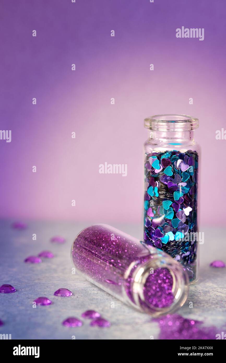Alle Arten von Glitter-Produkten auf rosa glitzerndem Hintergrund. Nahaufnahme von Fläschchen, Flaschen mit verschiedenen Glitzer-Make-up in Neonpink, Blau und Türkis Stockfoto