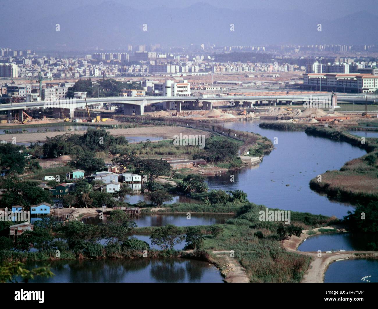 Ha Wan Village und Shenzhen River (Mitte rechts), von der Lok Ma Chau Polizeistation aus gesehen, 1992. Die neue Lok Ma Chau Border Crossing Point Bridge befindet sich ganz oben auf dem Foto und Shenzhen City (Festland China) ist in der Ferne. Stockfoto