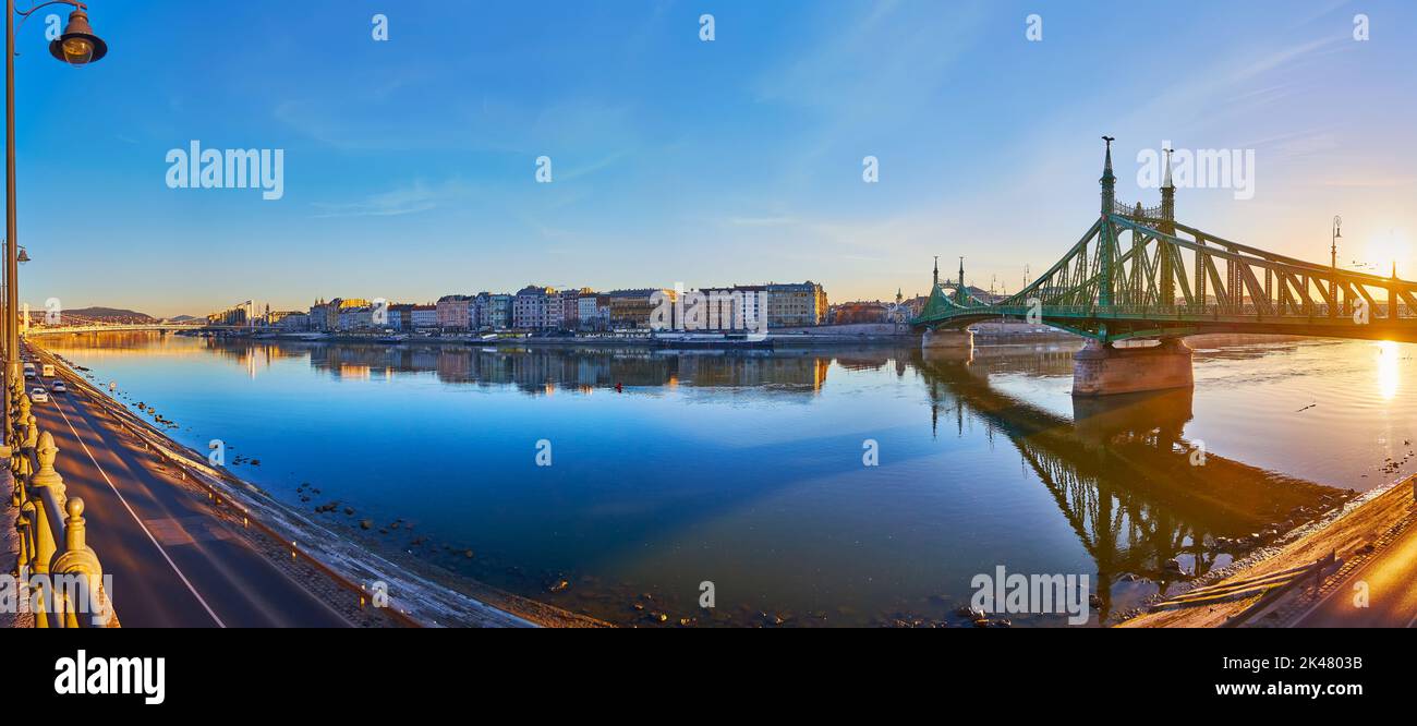 Genießen Sie den hellen Sonnenaufgang von Budapest vom Ufer der Donau aus mit Blick auf die Freiheitsbrücke und den goldenen Sonnenaufgang dahinter, Budapest, Hun Stockfoto