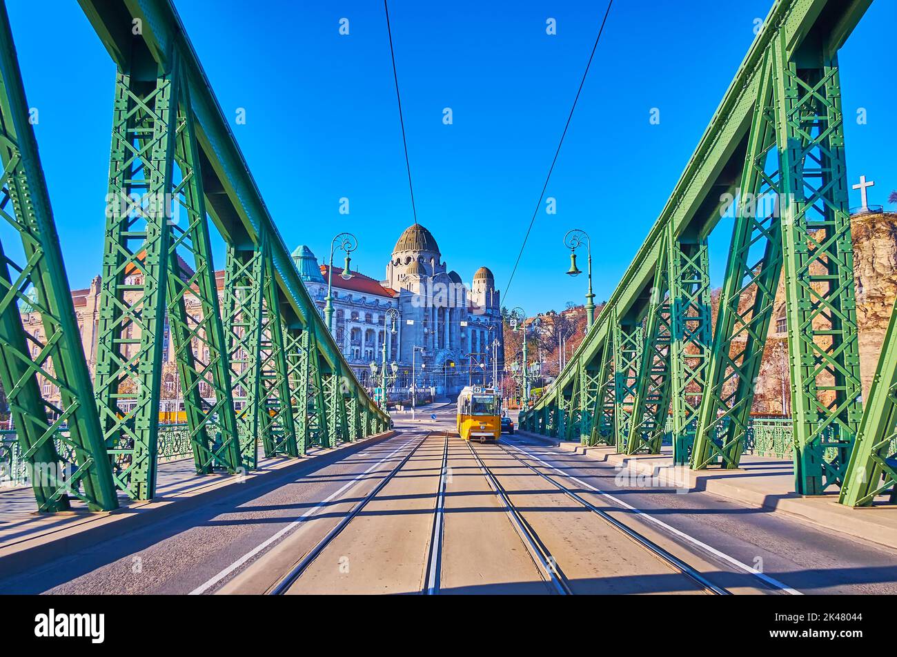 Die gelbe Straßenbahn auf der Freiheitsbrücke gegen das Steingebäude des Gellert Hotels und der Thermalbäder, Budapest, Ungarn Stockfoto
