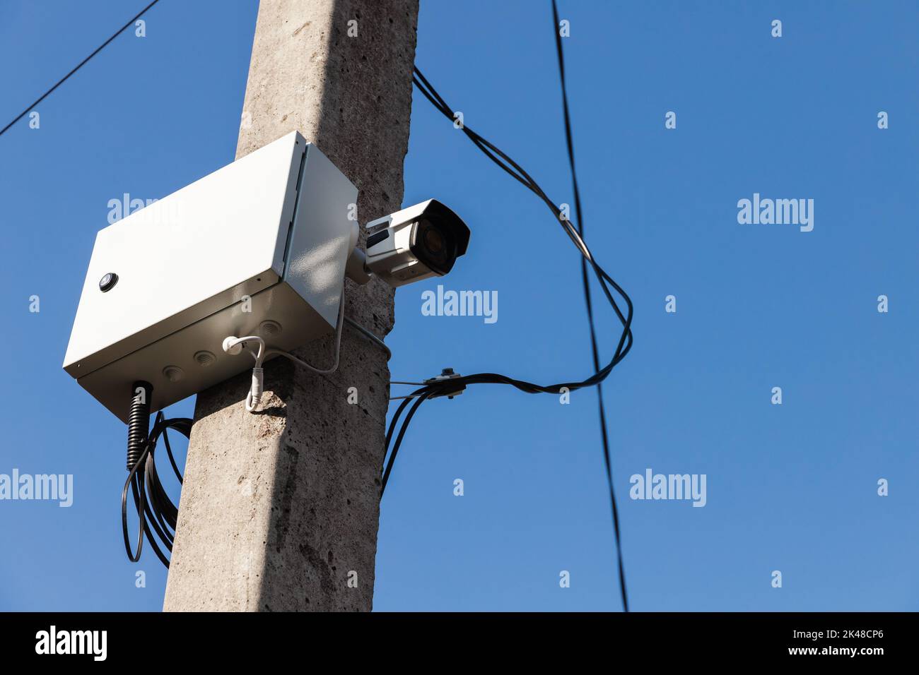Die Closed-Circuit-Fernsehkamera ist an einem Betonmast unter blauem Himmel montiert. CCTV-Überwachung ist im Gange Stockfoto