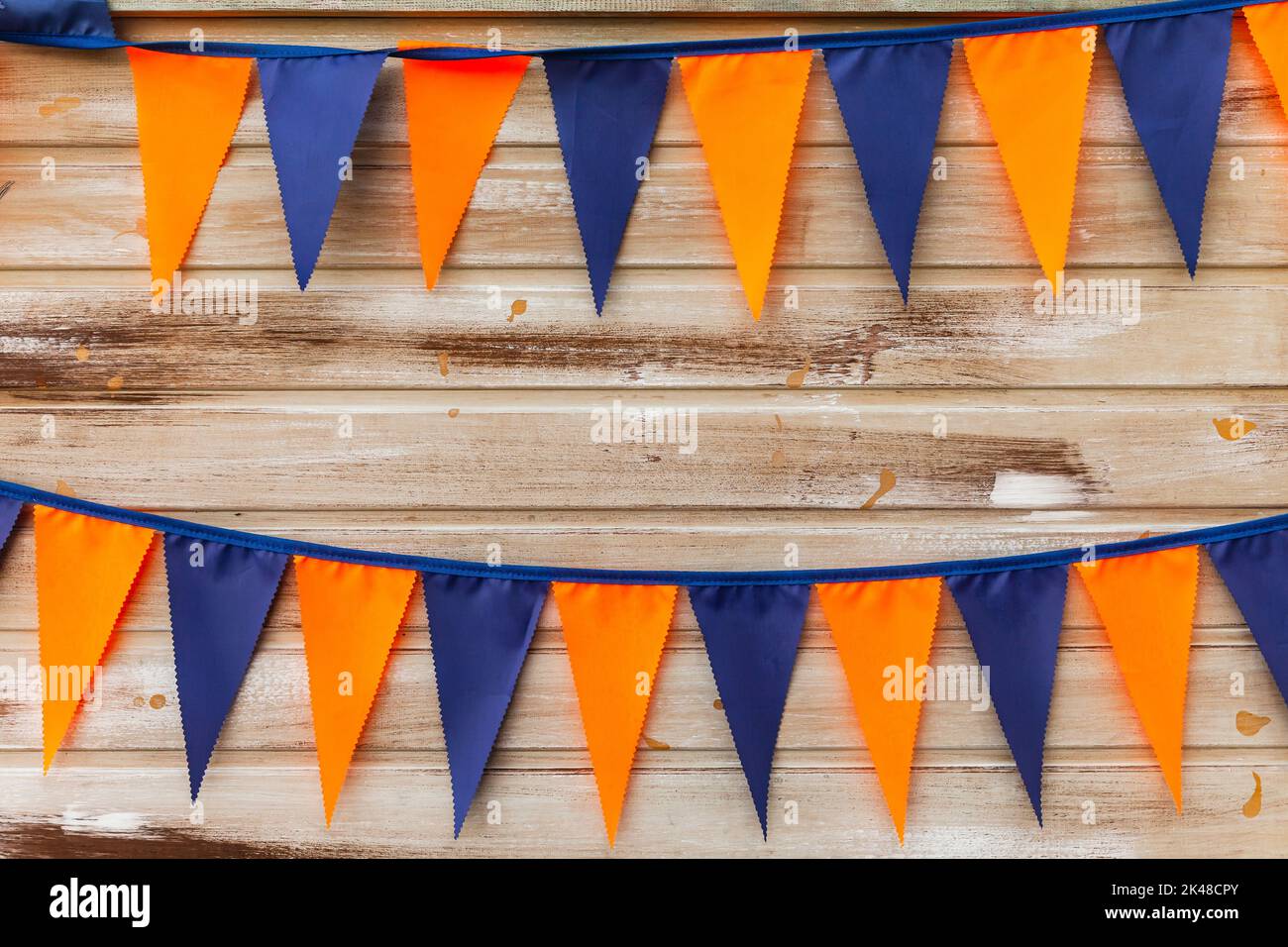 Bunte Dreiecksflaggen hängen an Seilen auf Holzwandhintergrund Stockfoto