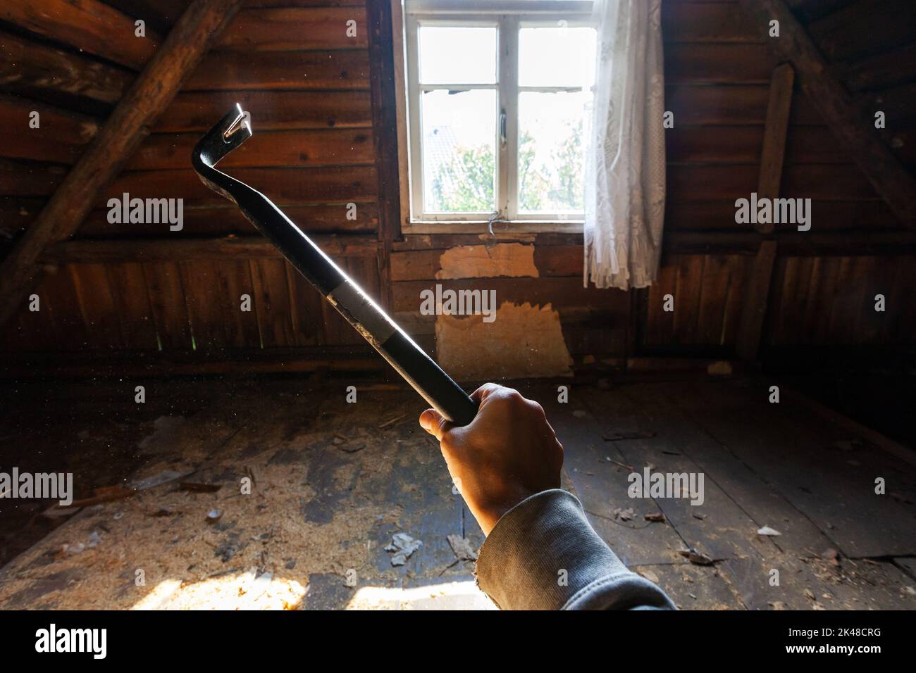 Schwarzer Nagelzieher in männlicher Hand, alter Holzhausabriss ist im Gange Stockfoto