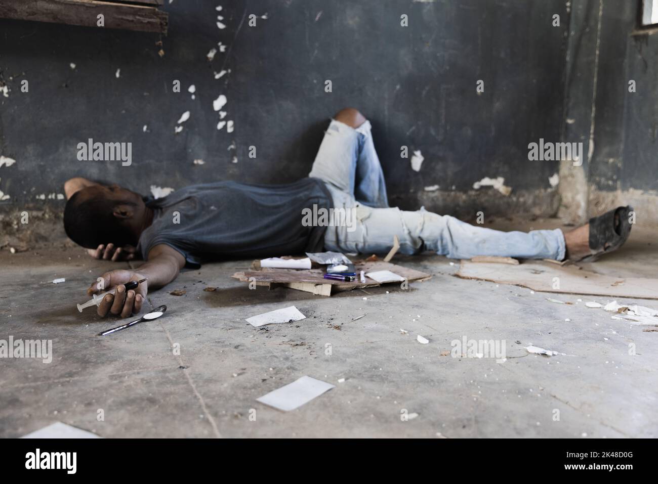 Menschliche Hand eines Drogenabhängigen und eine Spritze mit narkotischer Spritze auf dem Boden liegend. Anti-Drogen-Konzept. Stockfoto