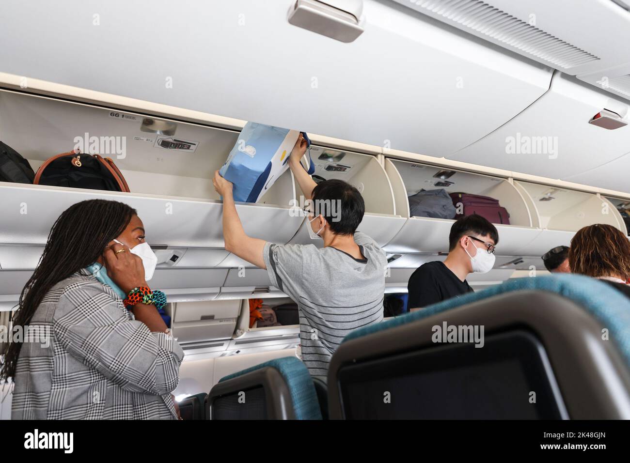 Reisende stellen Handgepäck im Gepäckraum eines Flugzeugs auf, wenn sie während des 19. Covid über den internationalen Flughafen Hongkong reisen Stockfoto