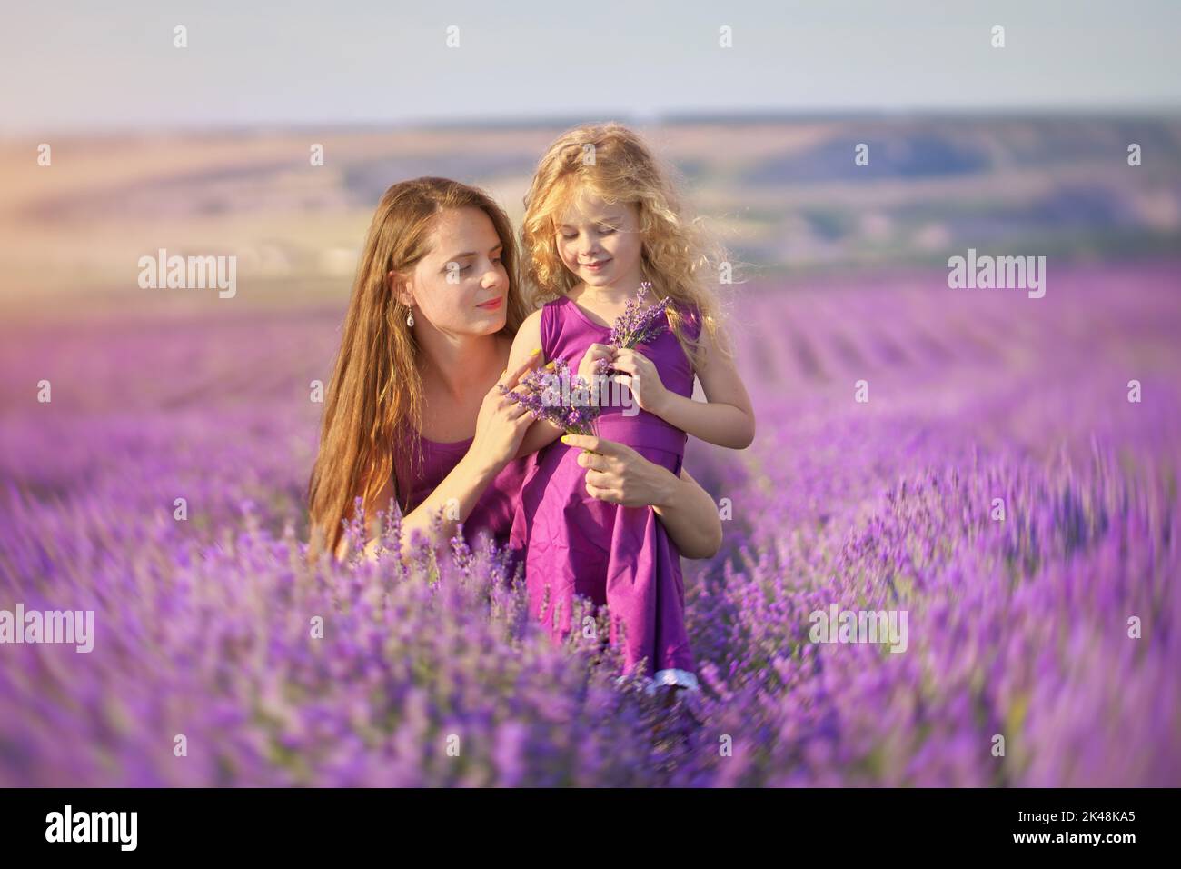 Kleines Mädchen und Mutter auf der Lavendelwiese. Familienpflege und Naturzusammensetzung. Stockfoto