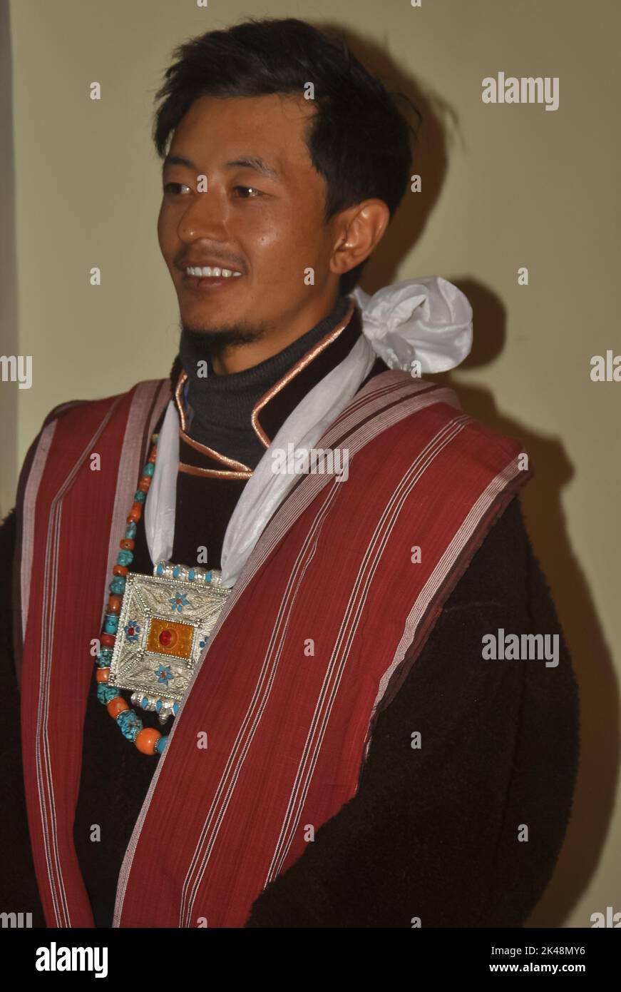 Nahaufnahme eines glücklichen Ladakhi Groom aus dem Zanskar-Tal, der seitwärts blickt und traditionelle Kleidung und Schmuck trägt Stockfoto