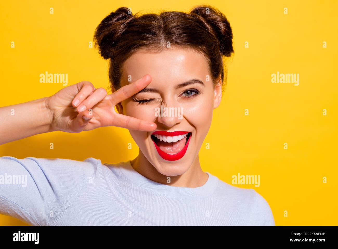 Foto von liebenswert gute Laune fröhlich weiblich zeigt V-Zeichen flirten mit Freund auf gelbem Hintergrund isoliert Stockfoto