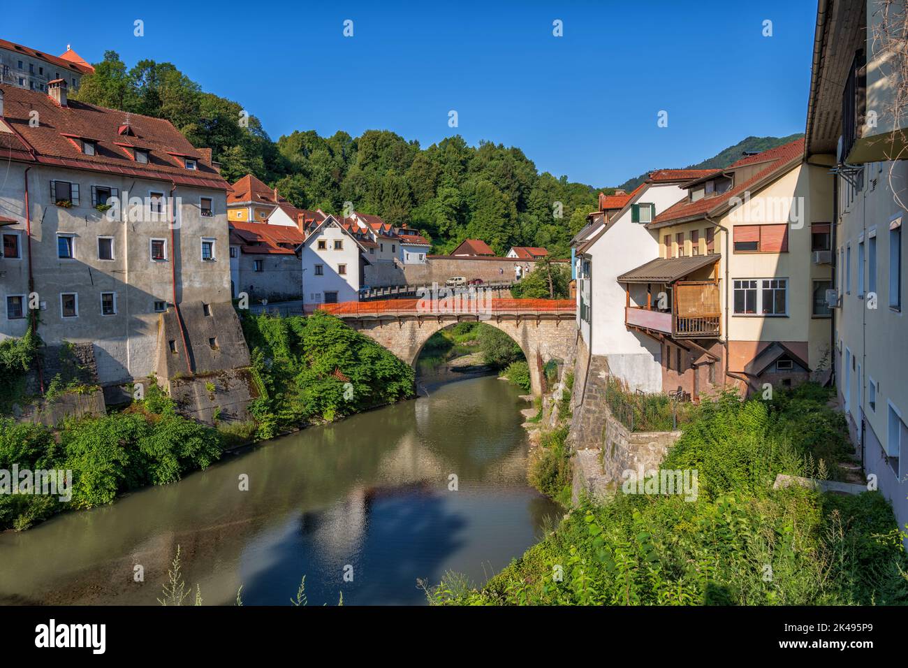 Skofja Loka Altstadt in Slowenien. Häuser am Fluss Selska Sora mit Blick auf die Kapuzinerbrücke, Oberkrain. Stockfoto