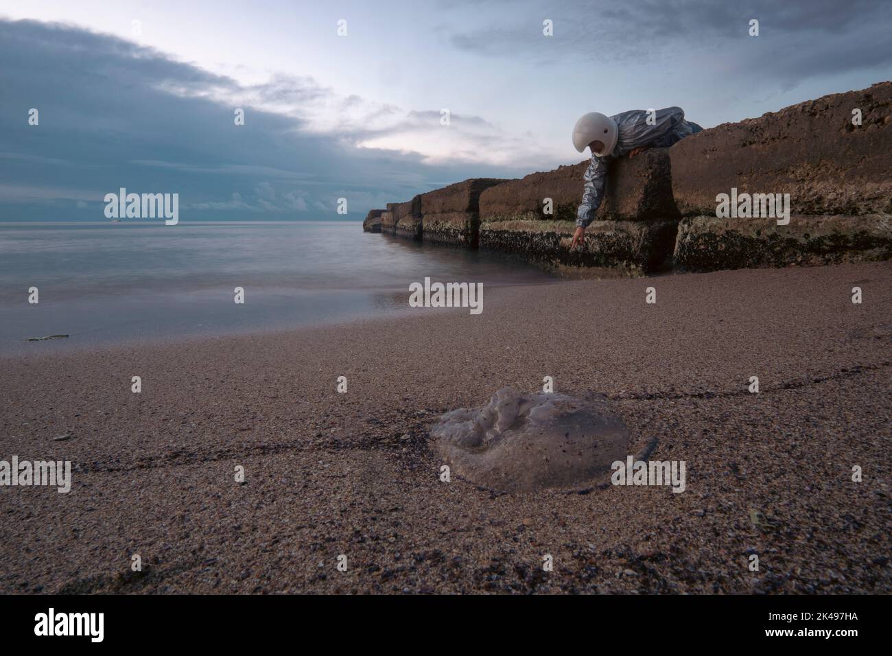 Astronaut mit 3D bedrucktem Helm, der auf eine Qualle zeigt. Konzept: Allein außerirdische Welten erkunden Stockfoto