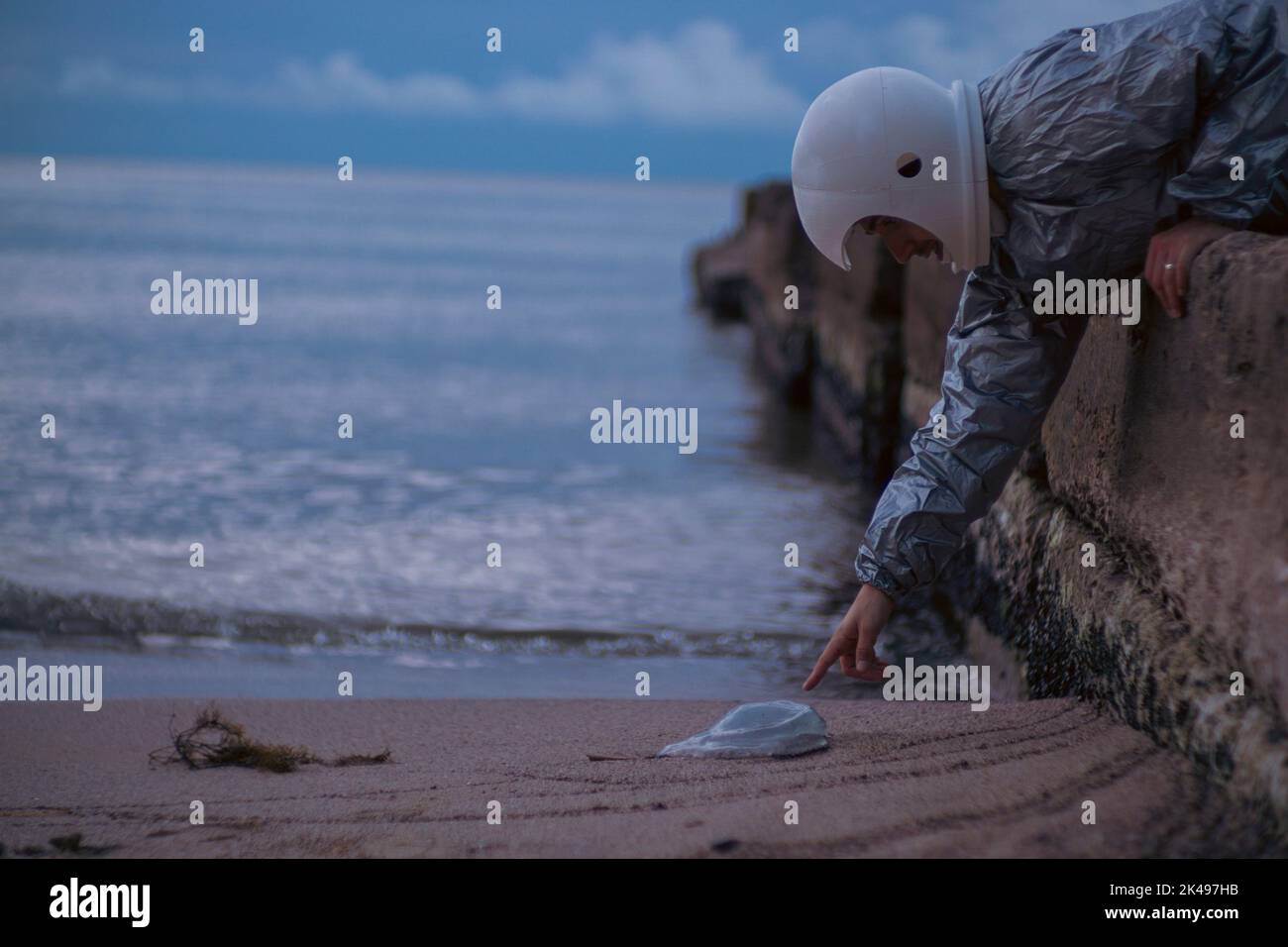 Astronaut mit 3D bedrucktem Helm, der auf eine Qualle zeigt. Konzept: Allein außerirdische Welten erkunden Stockfoto