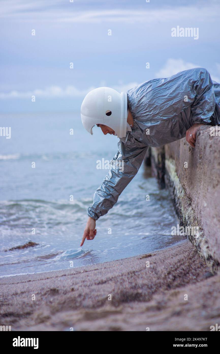 Astronaut mit 3D bedrucktem Helm, der auf eine Qualle zeigt. Konzept: Allein außerirdische Welten erkunden Stockfoto