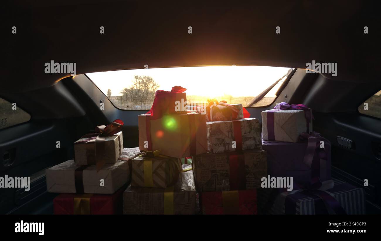 Viele Geschenke im Kofferraum. Geschenkboxen im Auto. Wunderschön verpackte Pakete. Blick aus dem Inneren des Autos. Lieferservice. Spende, Charity-Konzept. Hochwertige Fotos Stockfoto