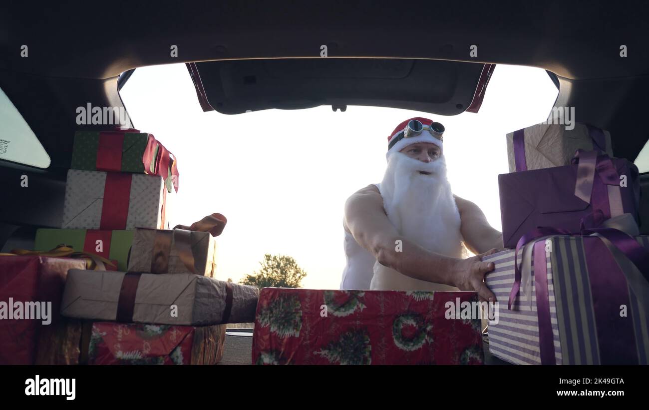 weihnachtsmann liefert Geschenke. Geschenke vom weihnachtsmann. Lieferservice. Deliveryman lädt Boxen. Geschenk-Boxen im Auto. Schön verpackte Pakete. Blick aus dem Inneren des Autos. Spende, Wohltätigkeit oder Lieferkonzept. Hochwertige Fotos Stockfoto