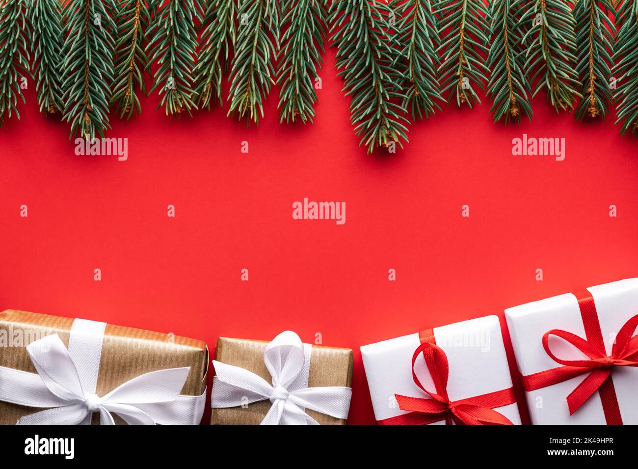 Kreative Weihnachten Hintergrund mit Weihnachten Geschenkboxen und Kiefernzweige auf rotem Hintergrund. Flach liegend, Draufsicht, Kopierbereich Stockfoto