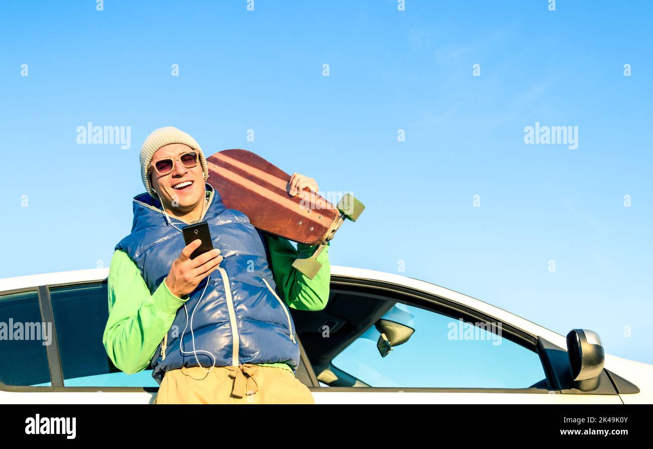 Junger Hipster-Mann mit Smartphone Musik neben seinem Auto hören - Konzept der modernen Technologien gemischt mit einem Vintage-Reise-Lifestyle - Herbst Winter Stockfoto